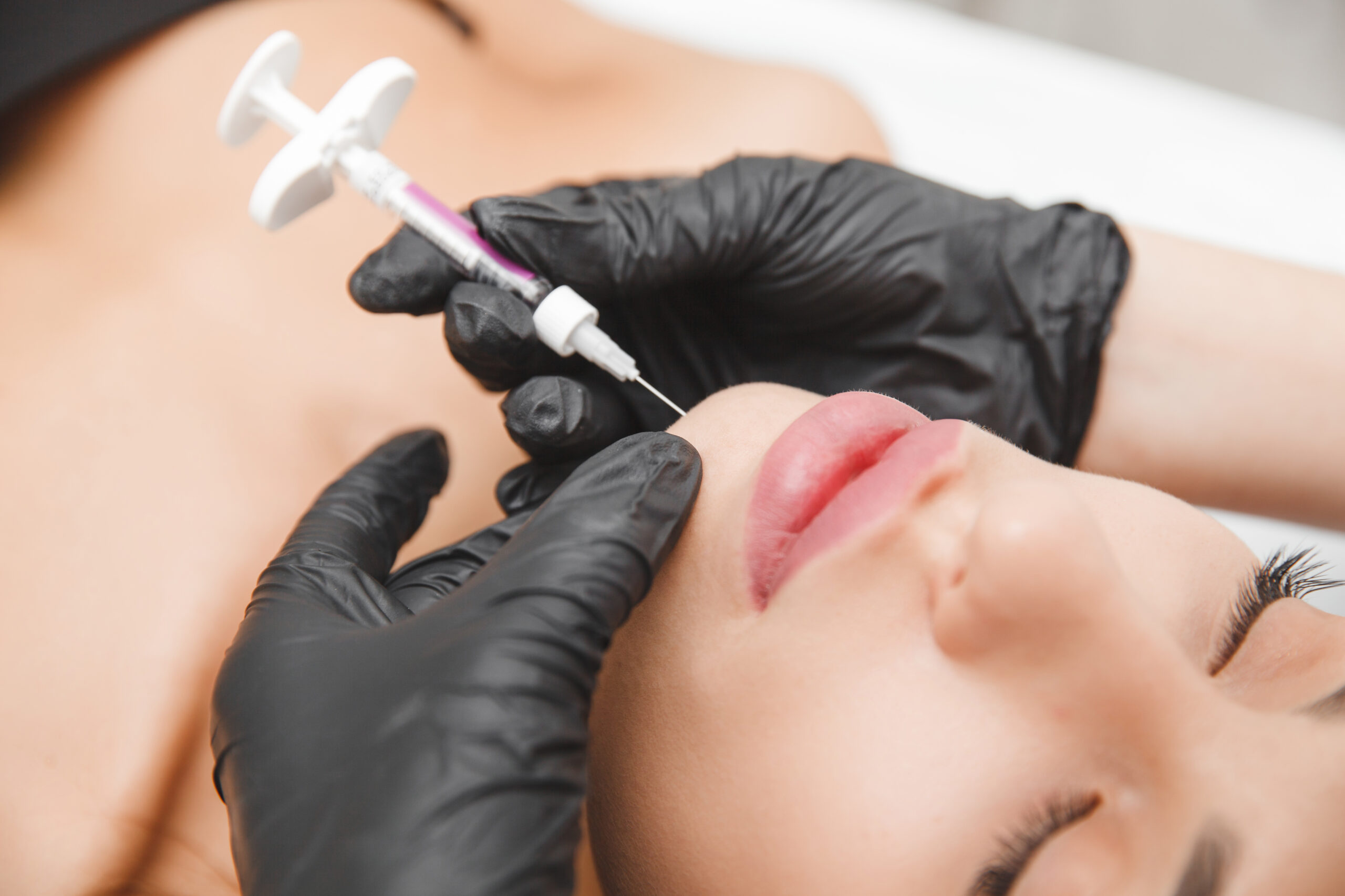 A cosmetologist makes lipolytic injections to burn fat on a woman's chin against a double chin. Women's aesthetic cosmetology in a beauty salon.The concept of cosmetology.