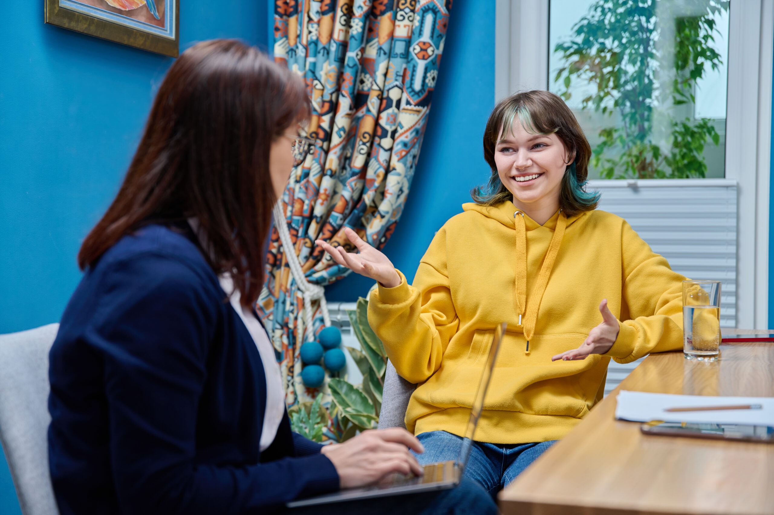 Teenage girl college student talking with counselor, psychologist in office